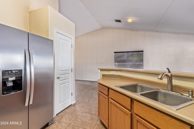 kitchen with stainless steel fridge, light tile patterned flooring, sink, and vaulted ceiling