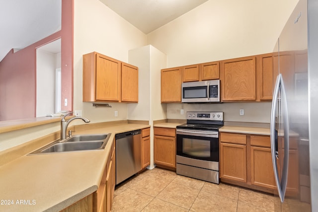 kitchen with high vaulted ceiling, sink, light tile patterned floors, appliances with stainless steel finishes, and kitchen peninsula