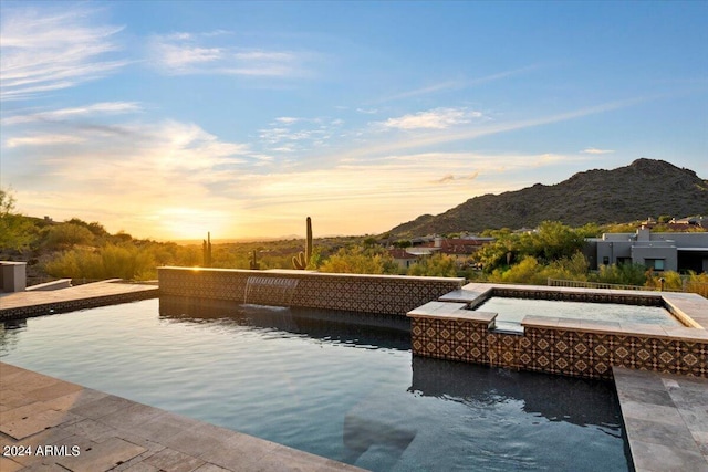 pool at dusk featuring a mountain view