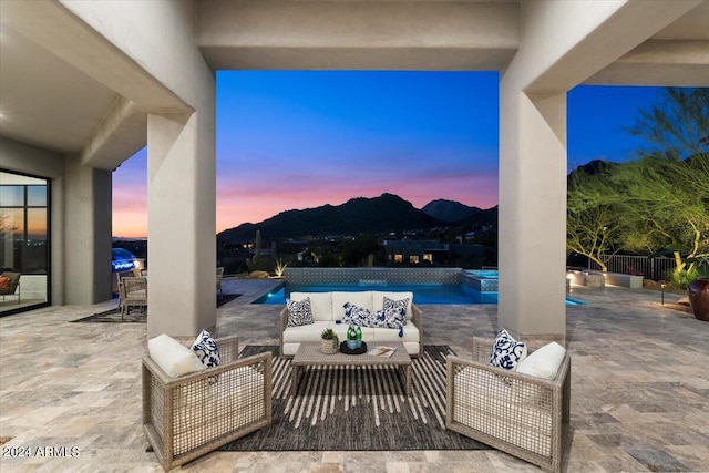 patio terrace at dusk featuring outdoor lounge area, a mountain view, and an in ground hot tub