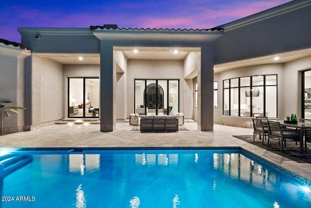 pool at dusk with an outdoor hangout area and a patio area