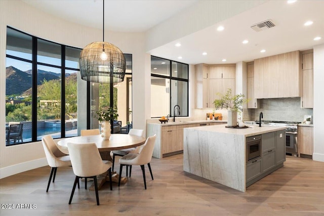 kitchen featuring a mountain view, pendant lighting, a center island with sink, and light hardwood / wood-style floors