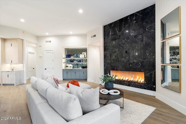 living room with a high end fireplace and wood-type flooring