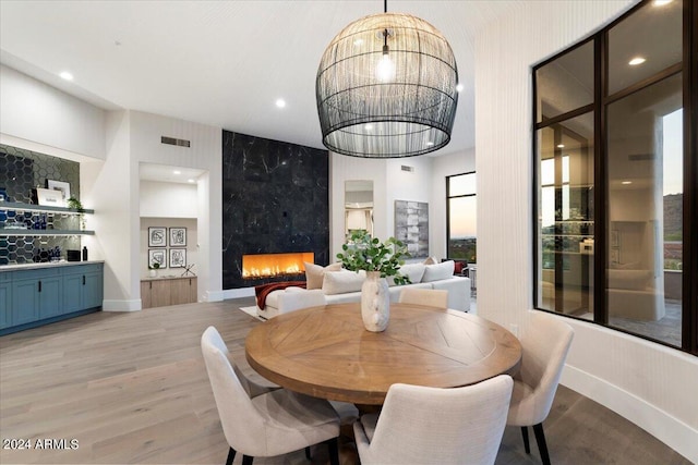 dining room with a fireplace, light wood-type flooring, a chandelier, and a wealth of natural light