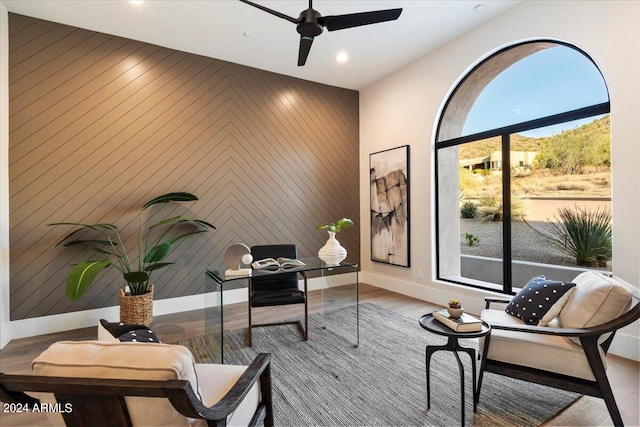 home office featuring wood walls, ceiling fan, and light hardwood / wood-style floors