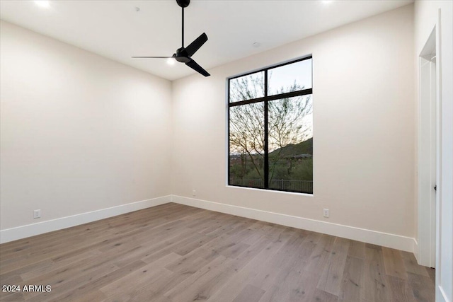 empty room with ceiling fan and light hardwood / wood-style floors