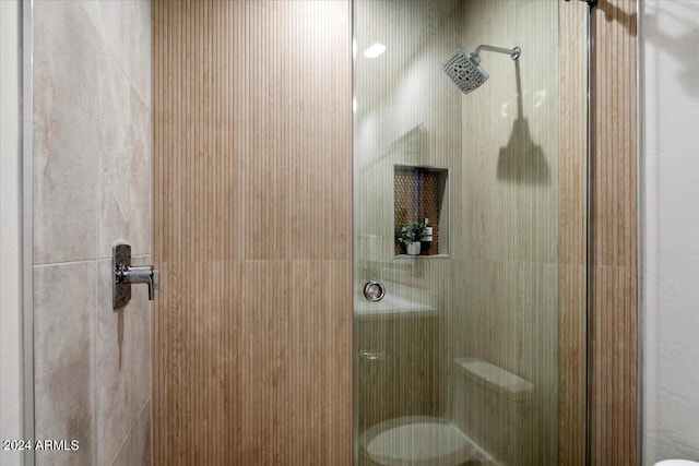 bathroom featuring a shower with door and toilet