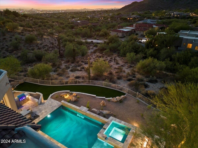 pool at dusk with an outdoor living space, an in ground hot tub, and a patio