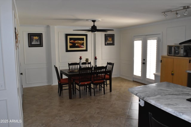 dining room with crown molding, french doors, track lighting, and a decorative wall