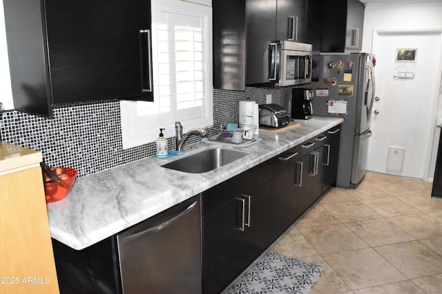 kitchen featuring stainless steel appliances, dark cabinetry, and a sink