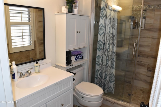 full bath featuring toilet, a stall shower, and vanity