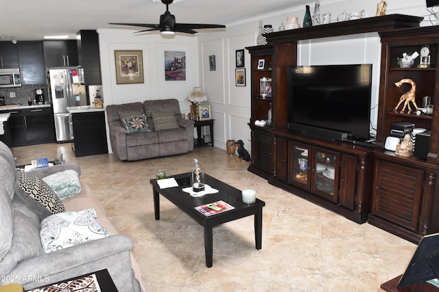 living area with crown molding, a decorative wall, and ceiling fan