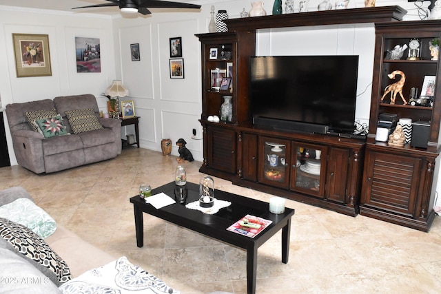 living room featuring a ceiling fan, crown molding, and a decorative wall