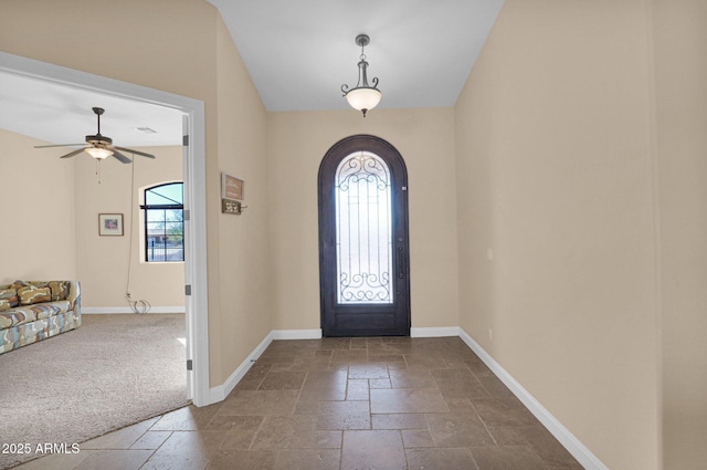 entrance foyer with ceiling fan and dark colored carpet