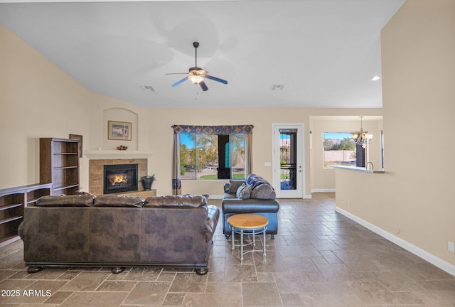 living room with ceiling fan with notable chandelier and a fireplace