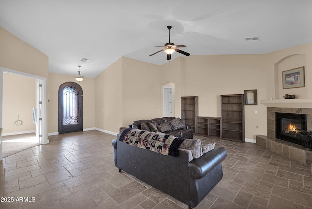 living room featuring a tiled fireplace, ceiling fan, and lofted ceiling