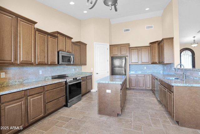 kitchen featuring sink, a center island, a towering ceiling, tasteful backsplash, and appliances with stainless steel finishes