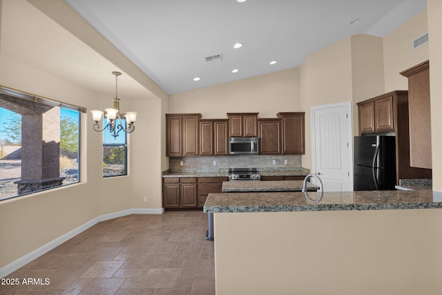 kitchen featuring kitchen peninsula, a chandelier, black fridge, range, and tasteful backsplash