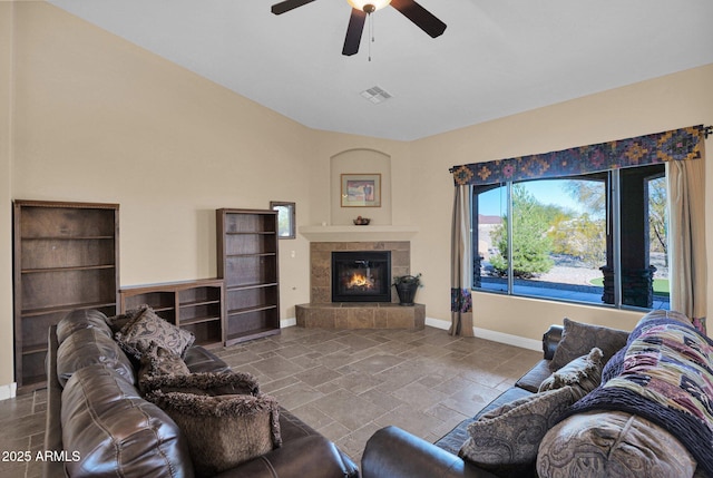 living room with a tiled fireplace and ceiling fan