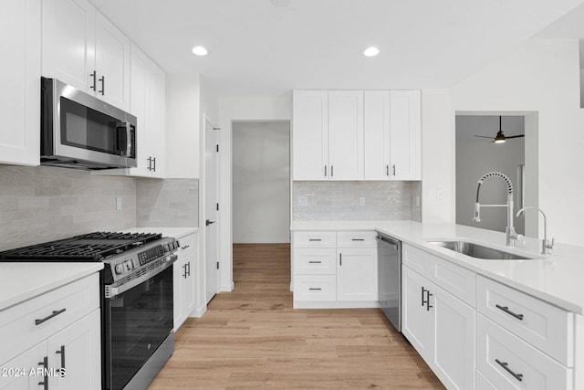 kitchen featuring appliances with stainless steel finishes, light wood-type flooring, ceiling fan, sink, and white cabinetry