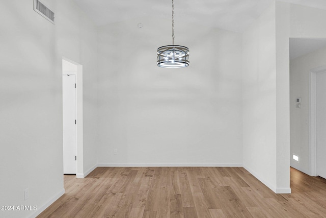 unfurnished dining area with light hardwood / wood-style flooring, high vaulted ceiling, and an inviting chandelier