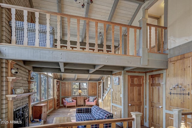 interior space featuring light wood-type flooring, beam ceiling, a fireplace, and wood walls