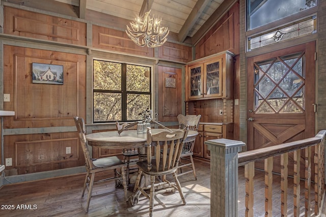 dining area with vaulted ceiling with beams, wooden walls, a chandelier, wooden ceiling, and hardwood / wood-style flooring