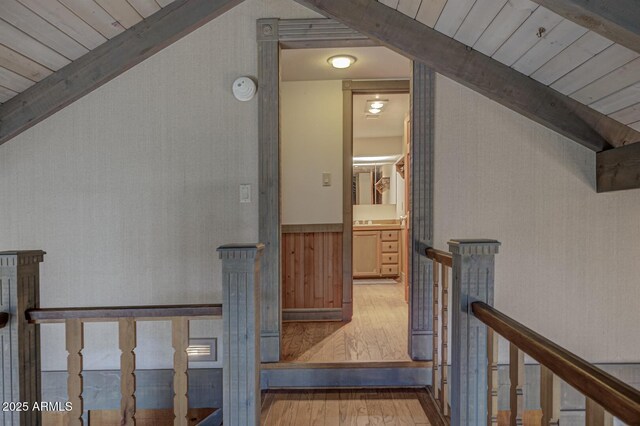 corridor with wooden ceiling, vaulted ceiling with beams, an upstairs landing, and wood finished floors