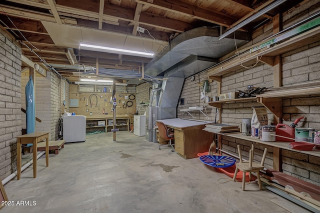 unfinished below grade area with brick wall, washer / clothes dryer, and a workshop area