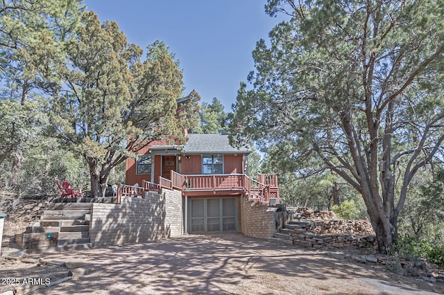 view of side of home with driveway, stairway, and a wooden deck