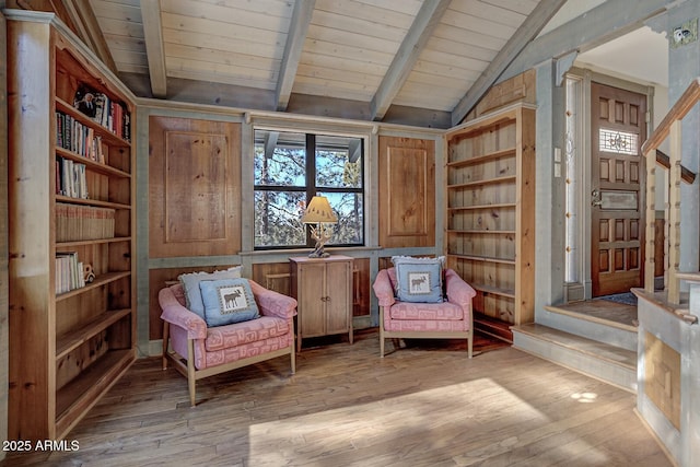 sitting room with lofted ceiling with beams, built in shelves, light wood-type flooring, and wood ceiling