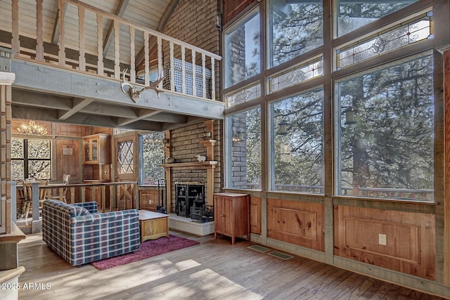 unfurnished living room with wooden ceiling, wood finished floors, beamed ceiling, wood walls, and high vaulted ceiling