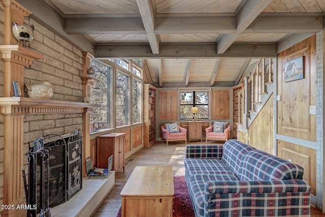 sitting room with wood-type flooring, a large fireplace, wood walls, wooden ceiling, and beamed ceiling