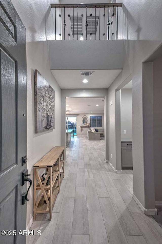 corridor with wood tiled floor, visible vents, and baseboards