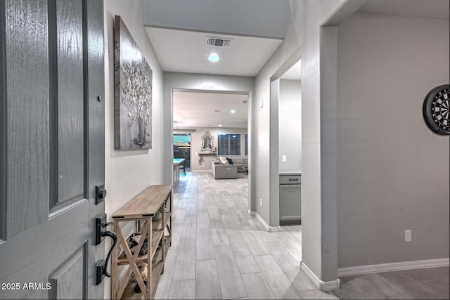 hall with wood finish floors, visible vents, and baseboards