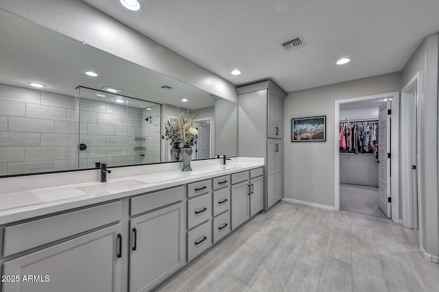 full bath featuring a walk in shower, recessed lighting, a sink, visible vents, and double vanity