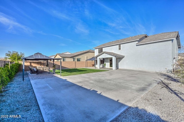 exterior space with a fenced backyard, a gazebo, a lawn, stucco siding, and a patio area