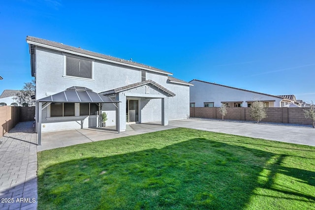 back of property featuring a yard, a fenced backyard, a patio, and stucco siding