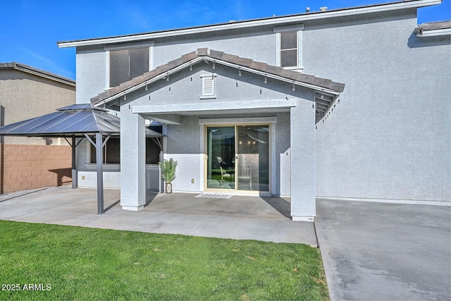 rear view of property featuring a patio area, fence, and stucco siding