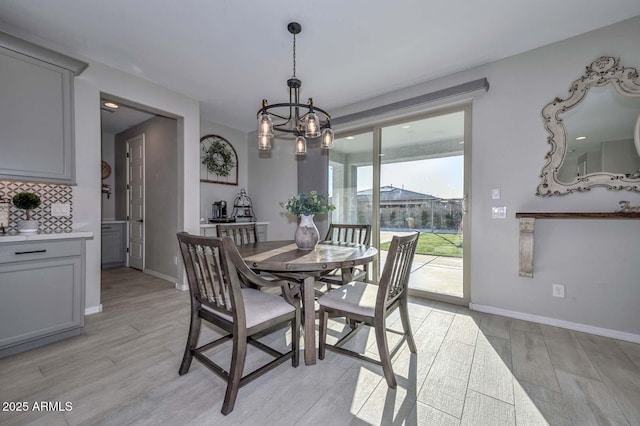 dining space with light wood-type flooring, baseboards, and a chandelier