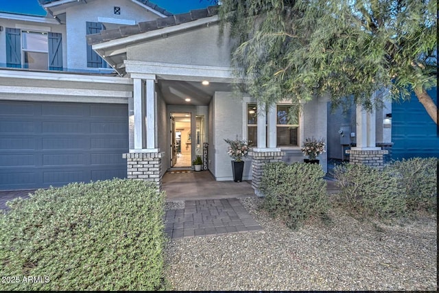 entrance to property featuring a garage and brick siding