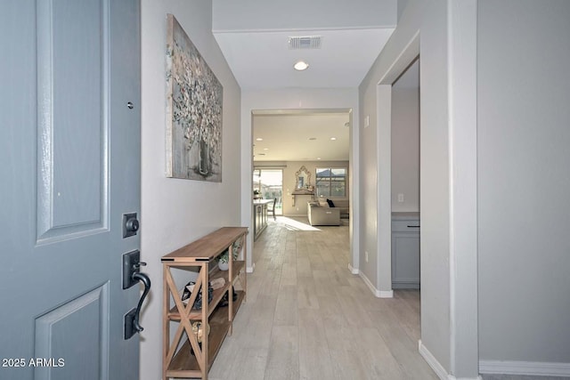 hall with light wood-style floors, recessed lighting, visible vents, and baseboards