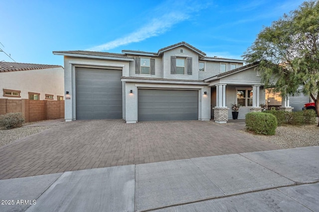 view of front of home featuring a tiled roof, decorative driveway, fence, and stucco siding