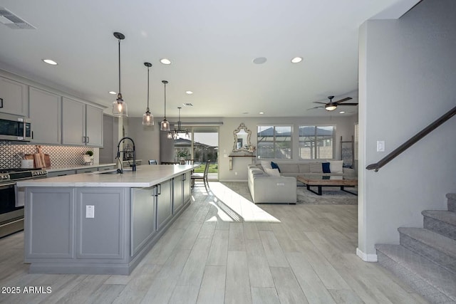 kitchen with visible vents, decorative backsplash, appliances with stainless steel finishes, gray cabinets, and light countertops