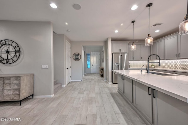 kitchen featuring gray cabinets, visible vents, backsplash, a sink, and high end refrigerator