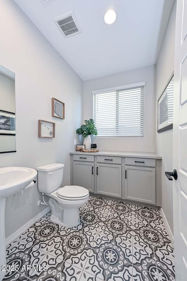 bathroom featuring visible vents, baseboards, toilet, lofted ceiling, and tile patterned flooring