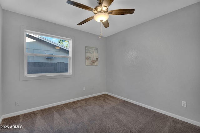 carpeted spare room featuring a ceiling fan and baseboards