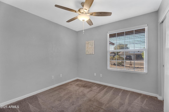 carpeted spare room featuring baseboards and a ceiling fan