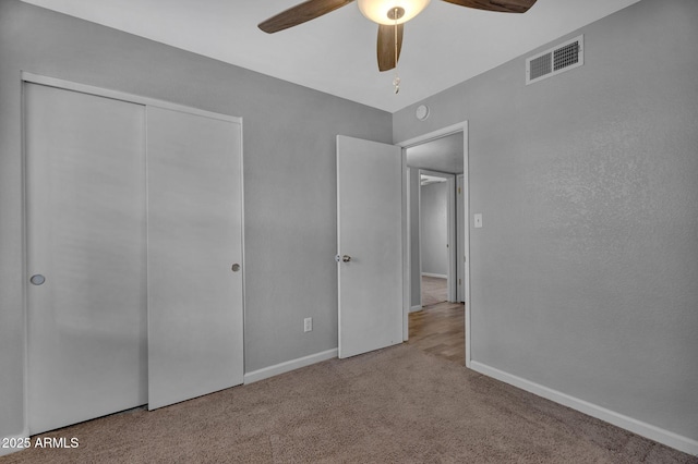 unfurnished bedroom with visible vents, a closet, baseboards, ceiling fan, and carpet