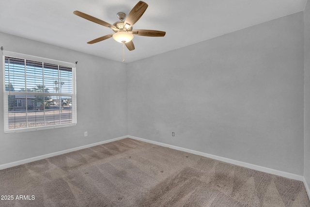 spare room with a ceiling fan, baseboards, and carpet